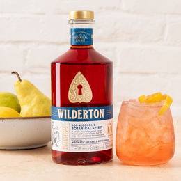 bottle of bittersweet aperitivo next to a glass of wilderton spritz and a bowl of pears