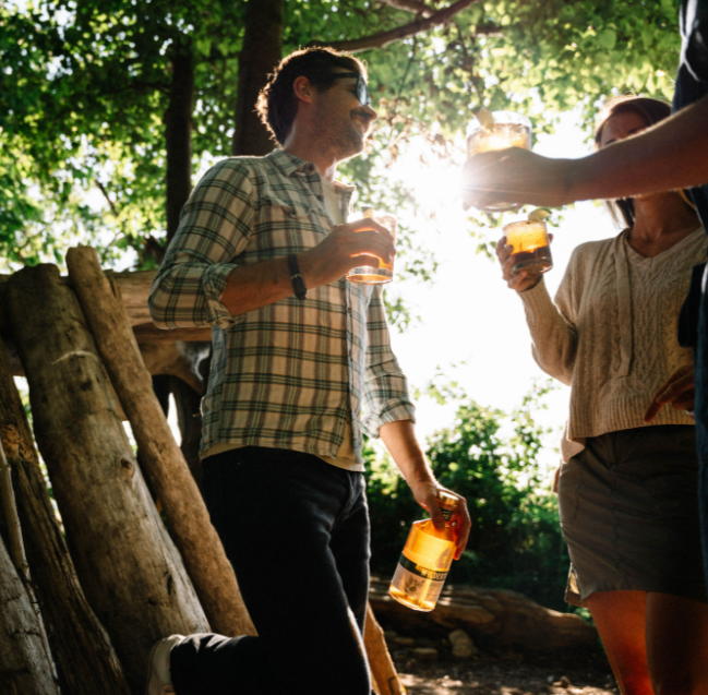 people in the woods holding drinks and a bottle of earthen