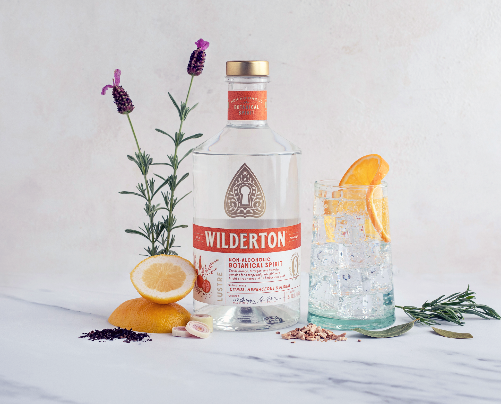 bottle of wilderton lustre surrounded by botanicals and a glass with a clear drink